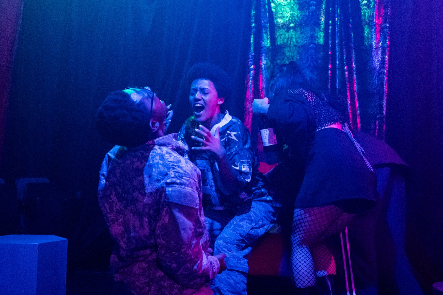 Three performers in blue and purple light during DECAPITATRIX