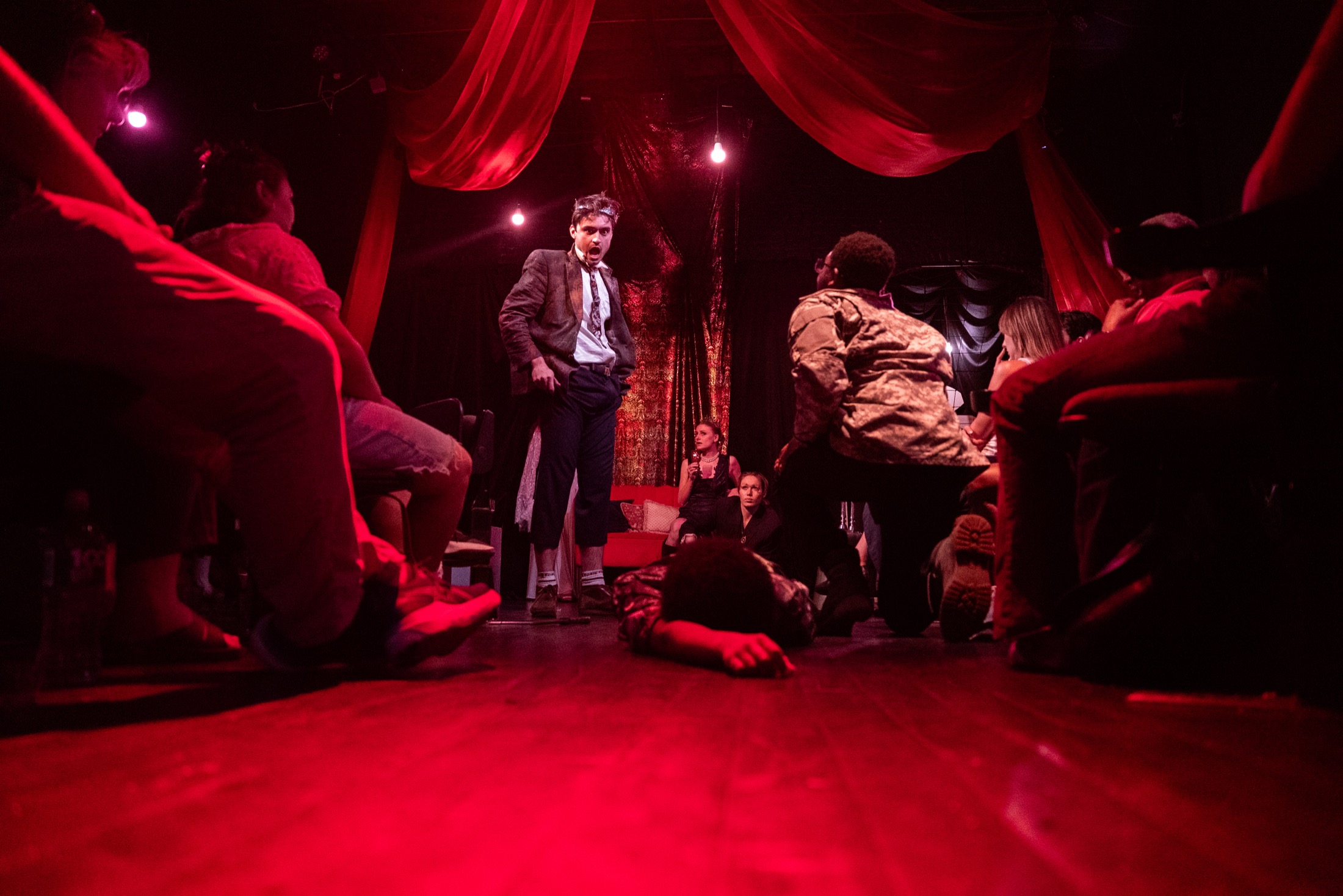 Herod performs in the red-lit DECAPITATRIX room while audience surrounds the stage
