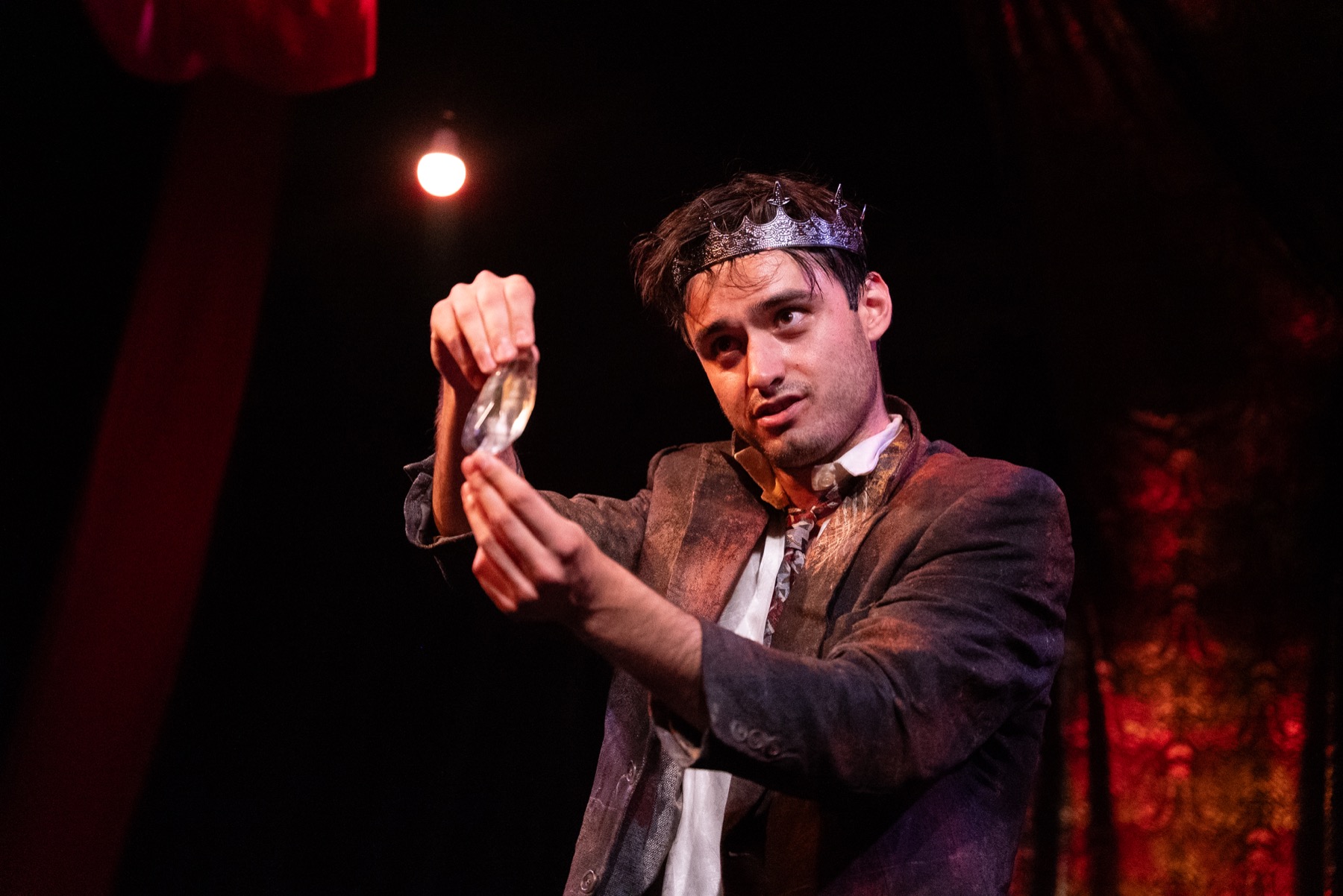 Herod holds up a glass vial in DECAPITATRIX