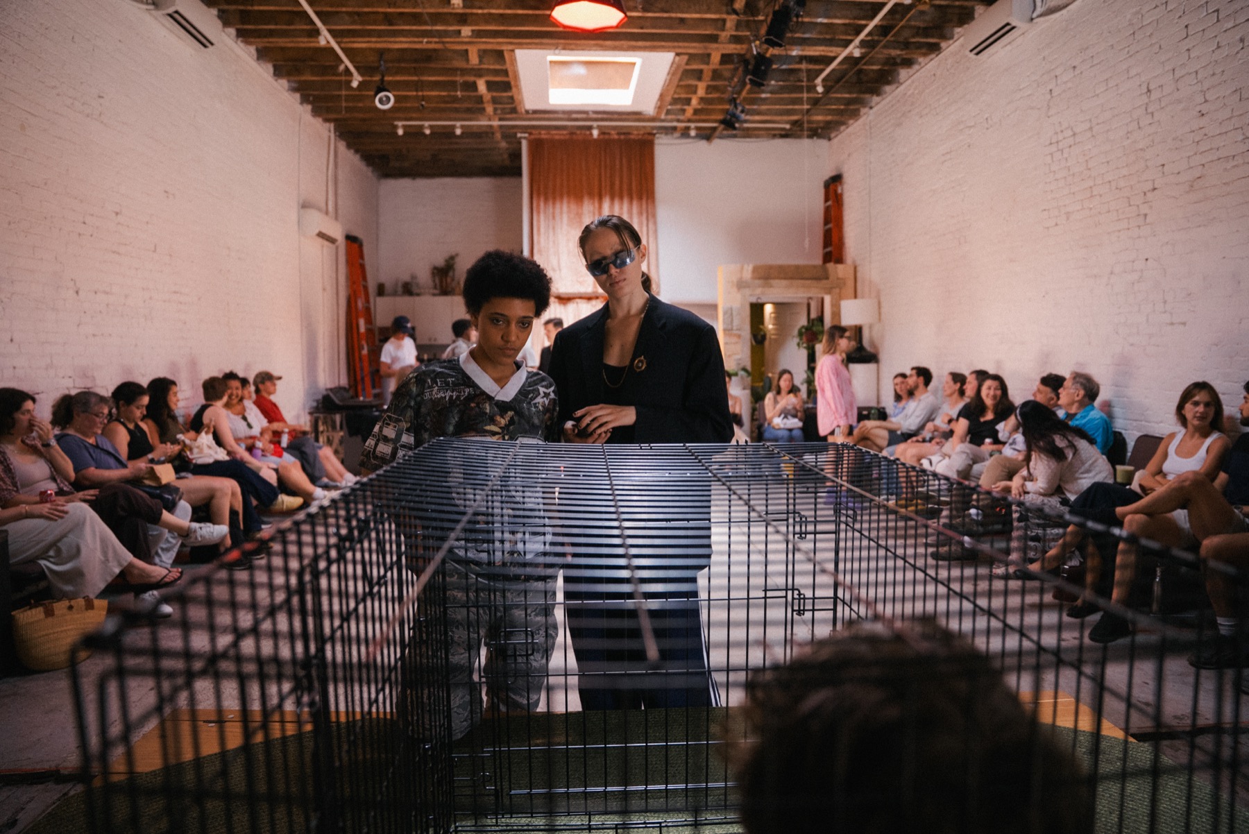 Performers and audience gather around the cage before DECAPITATRIX