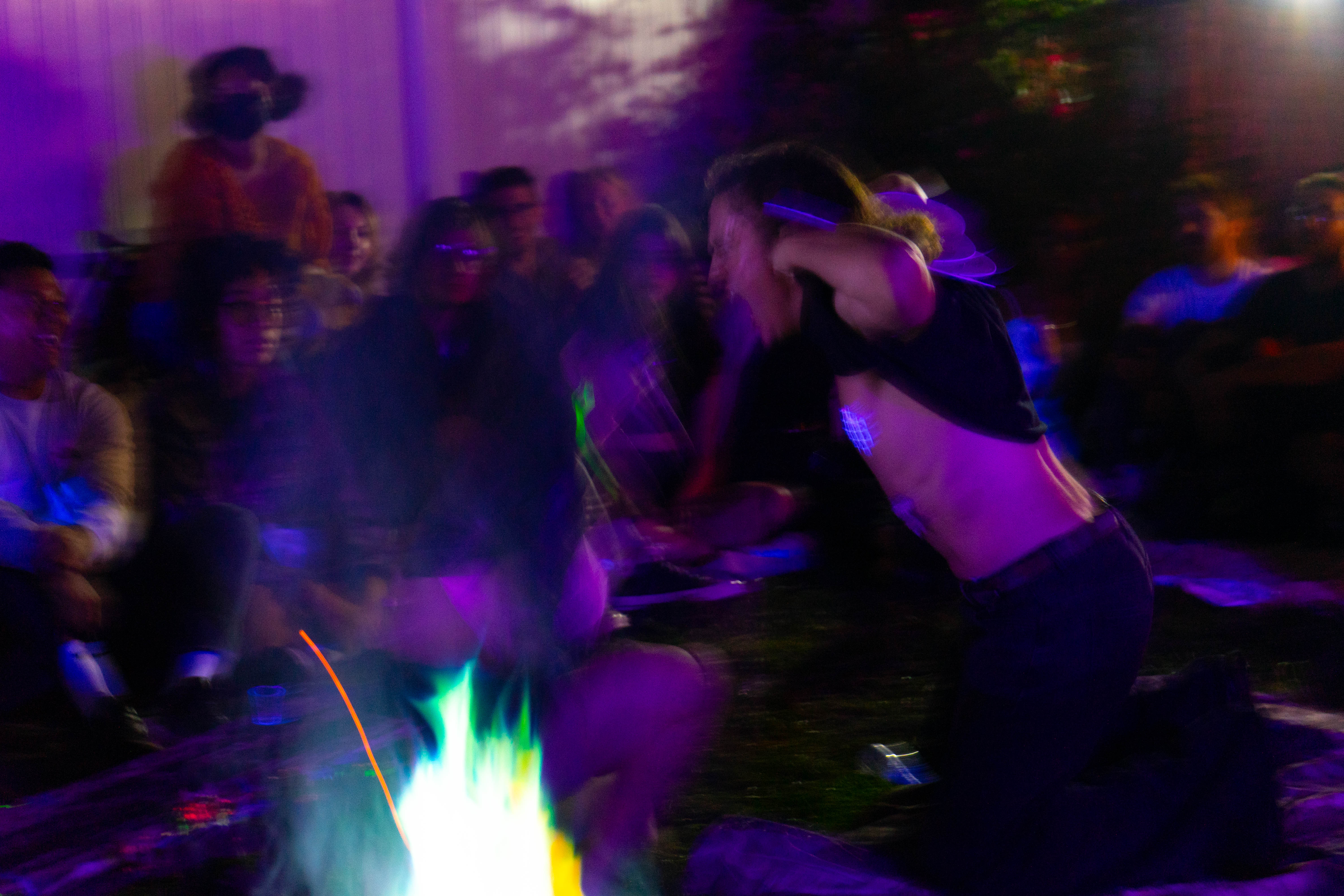 Performers gathered in a ritual-like backyard scene