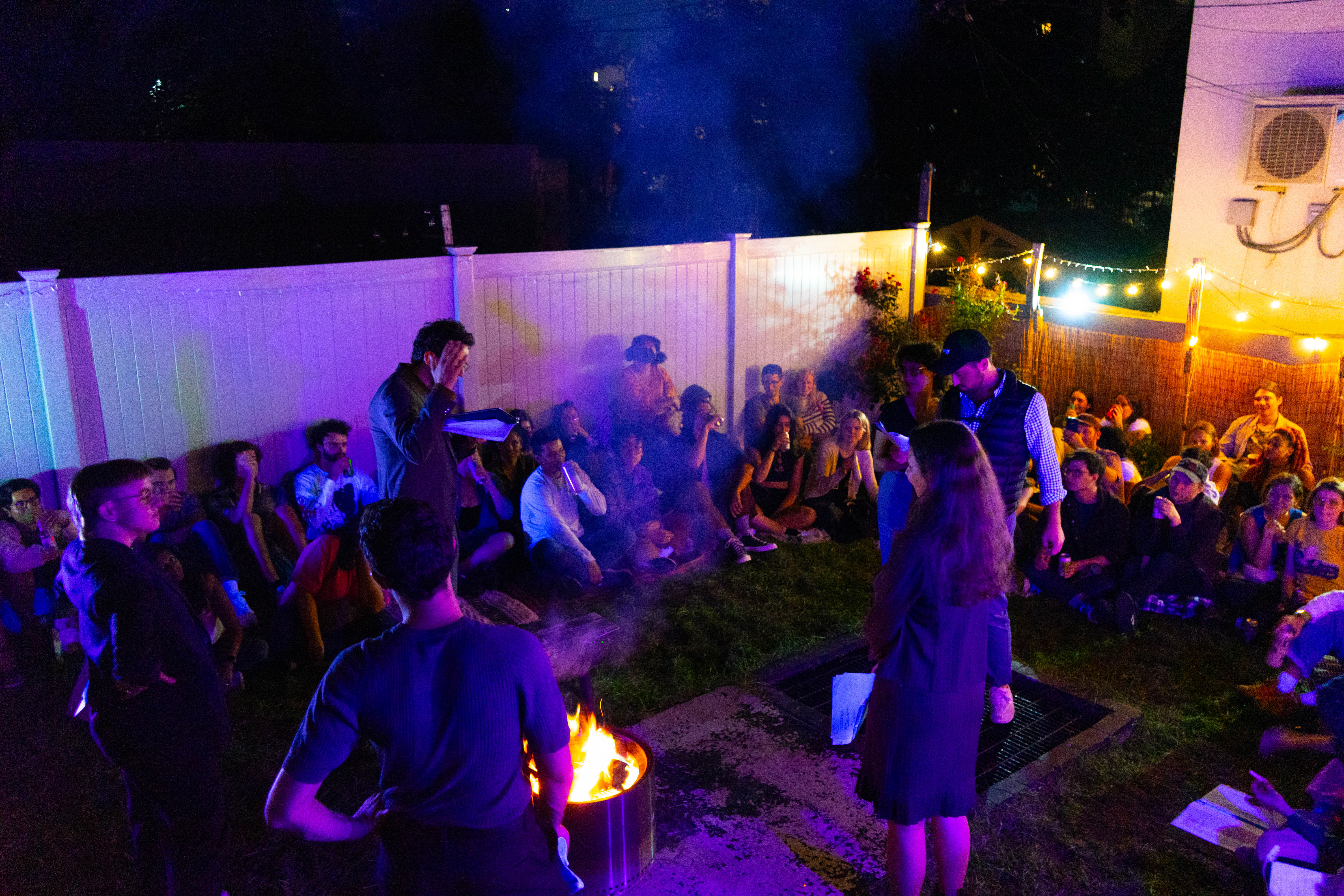 A performer reclines near a glowing firepit