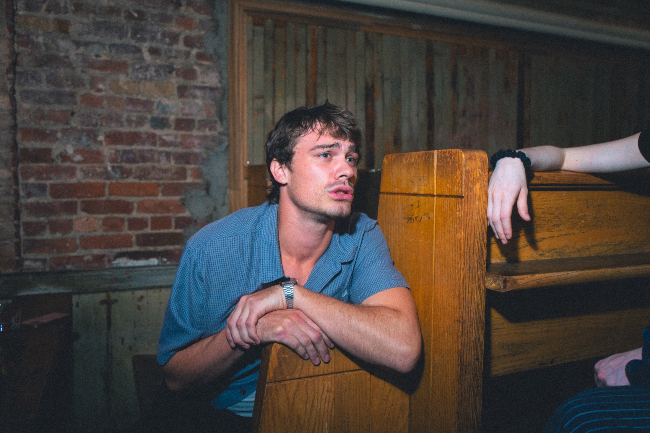 George Gibbs leans against a wooden bench in a night scene
