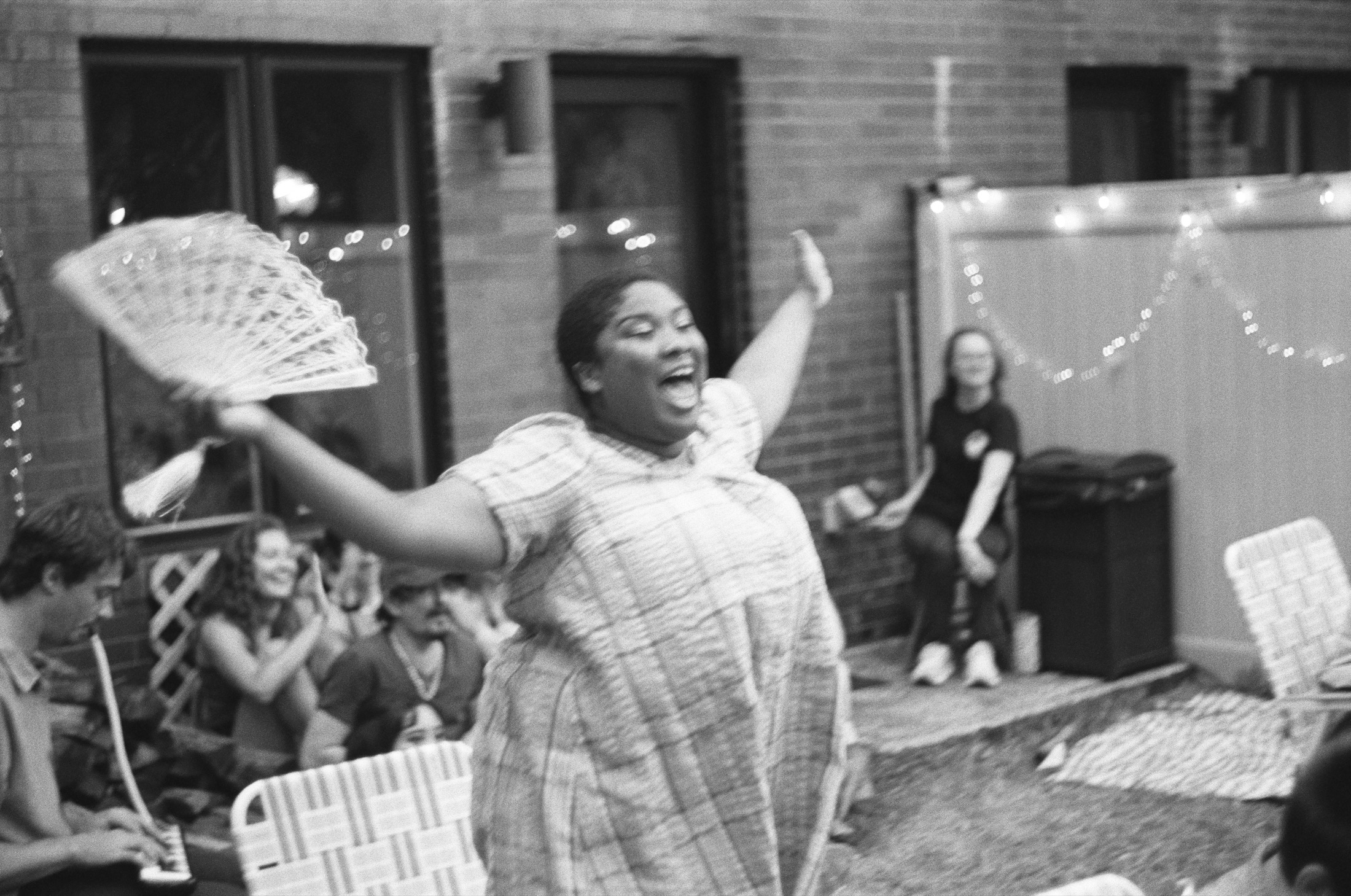 Mrs. Soames joyfully waves a fan in a black-and-white production photo