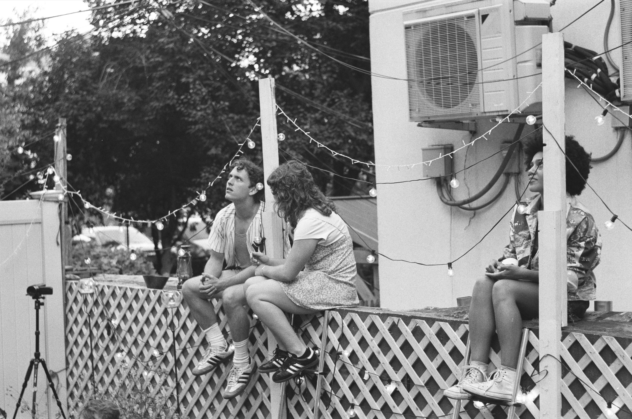 Performers sit on a lit porch in a black-and-white Our Town production photo
