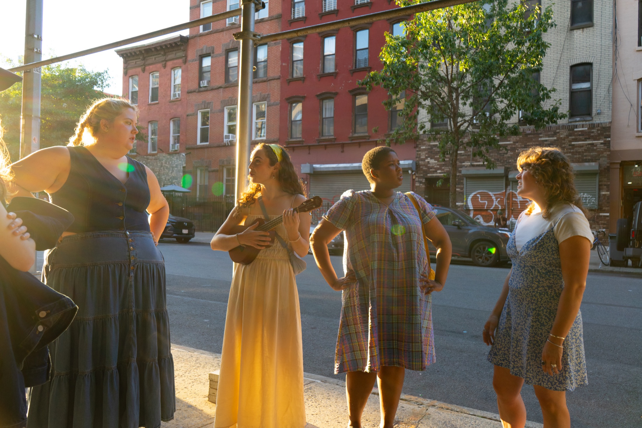 Performers stand on a Brooklyn sidewalk in golden light before Our Town