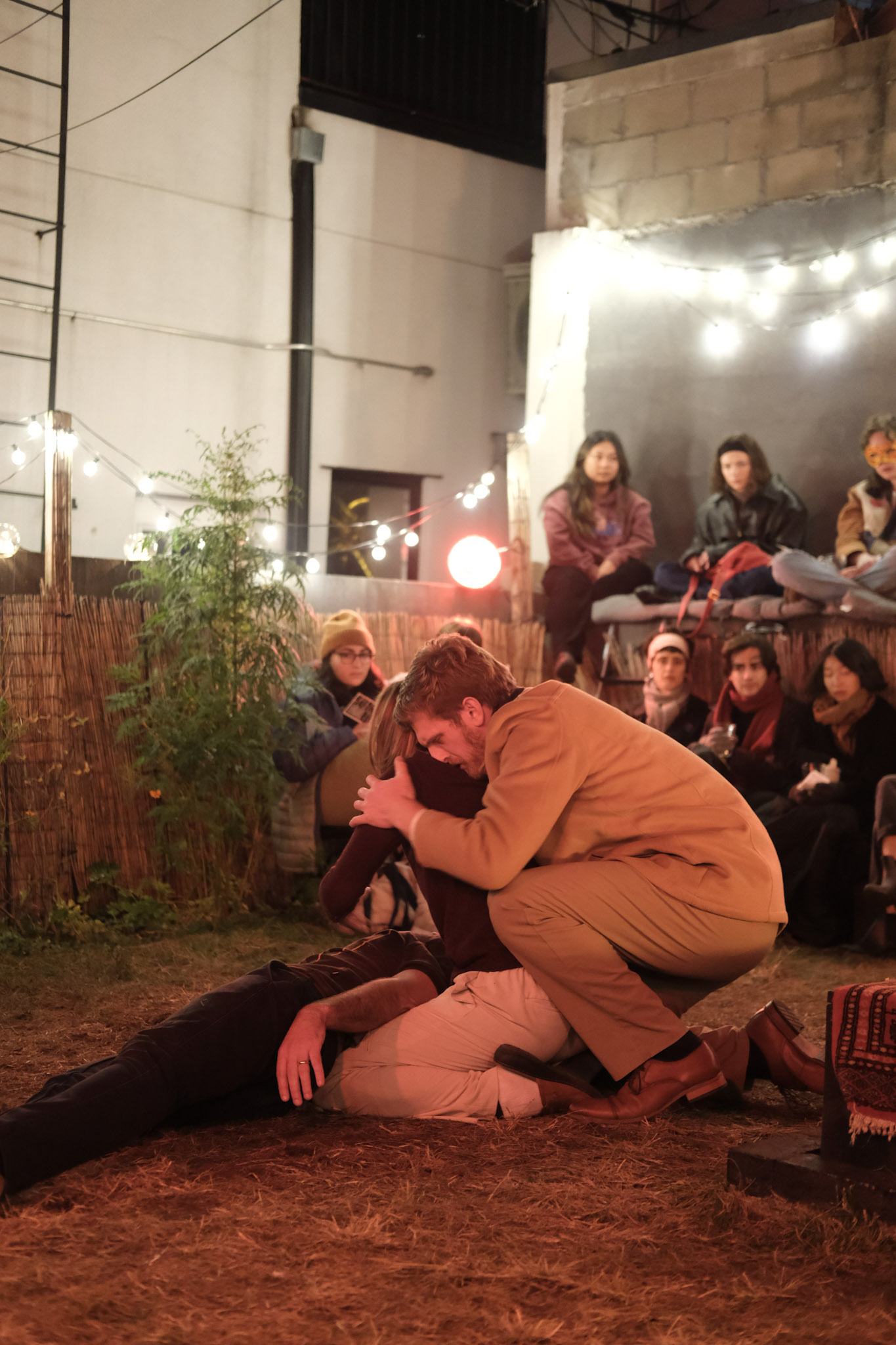 Romeo embraces Juliet on the ground while audience members watch nearby