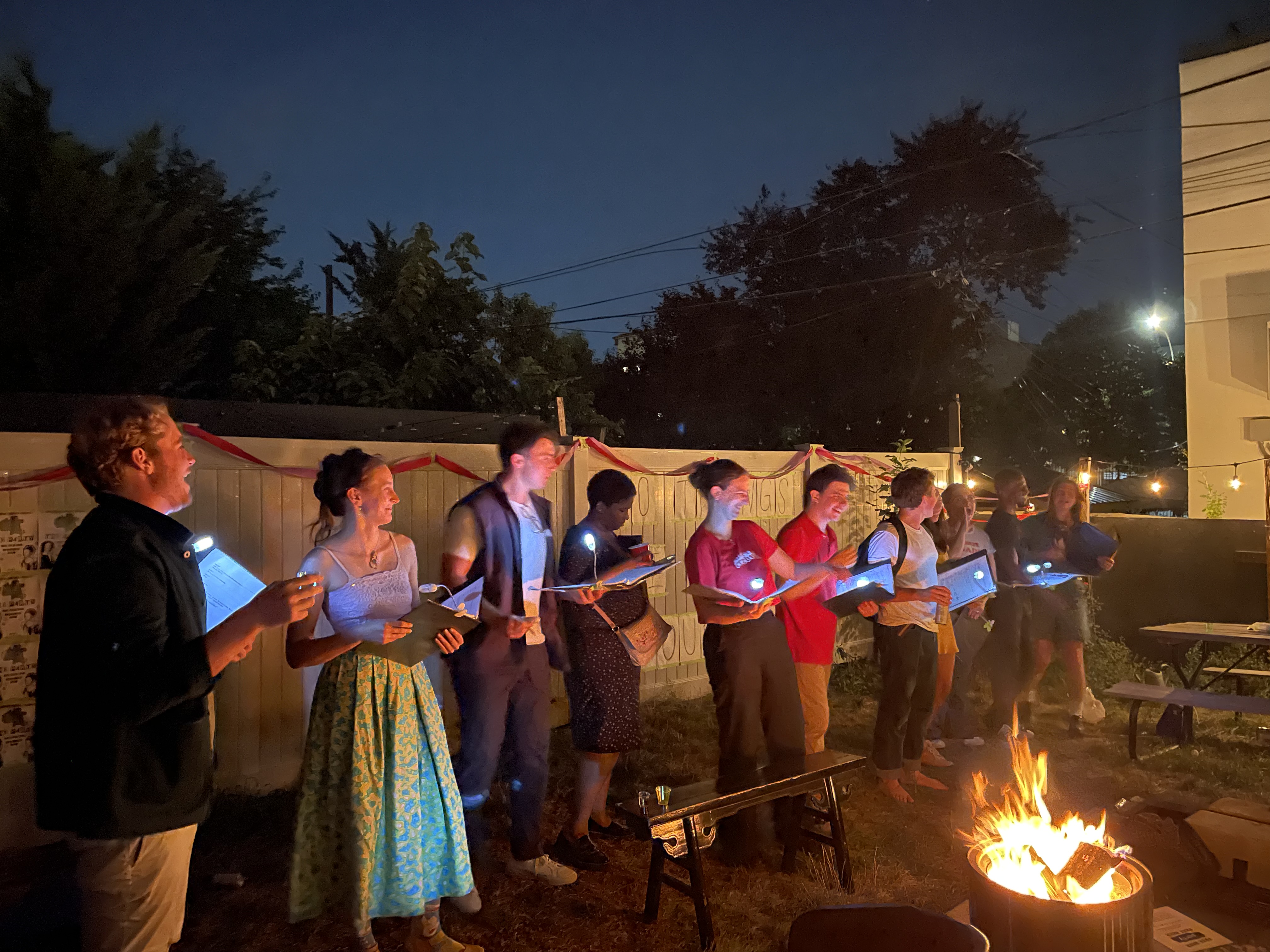 The company of 10 Things I Hate About You performs around a backyard firepit