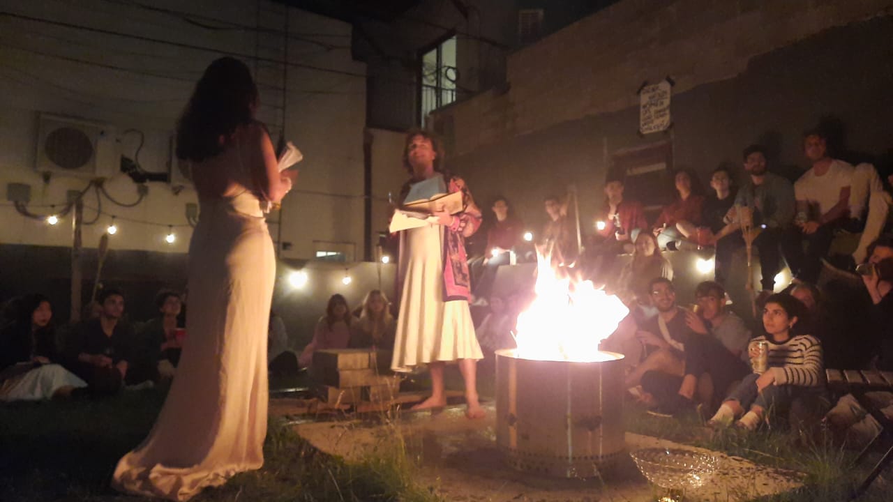 Two performers stand across a fire circle during The Bacchae