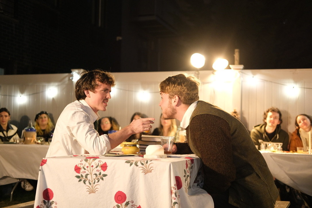 George and Nick lean toward one another across the dinner table