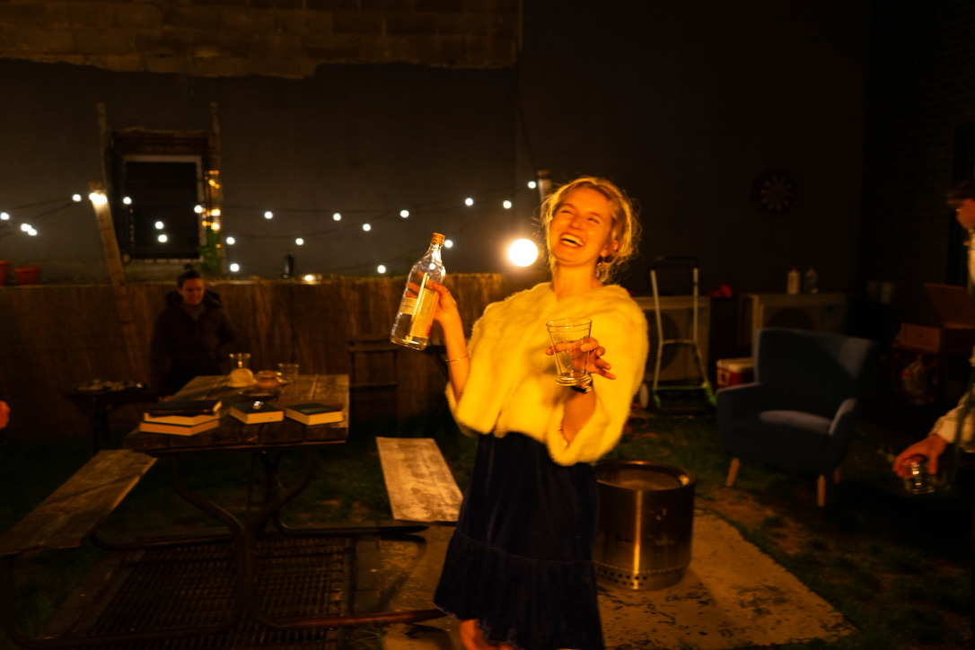 Honey laughs with a bottle and drink in hand during Who’s Afraid of Virginia Woolf