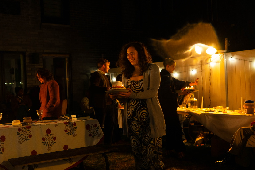 Martha carries plates through the dinner party
