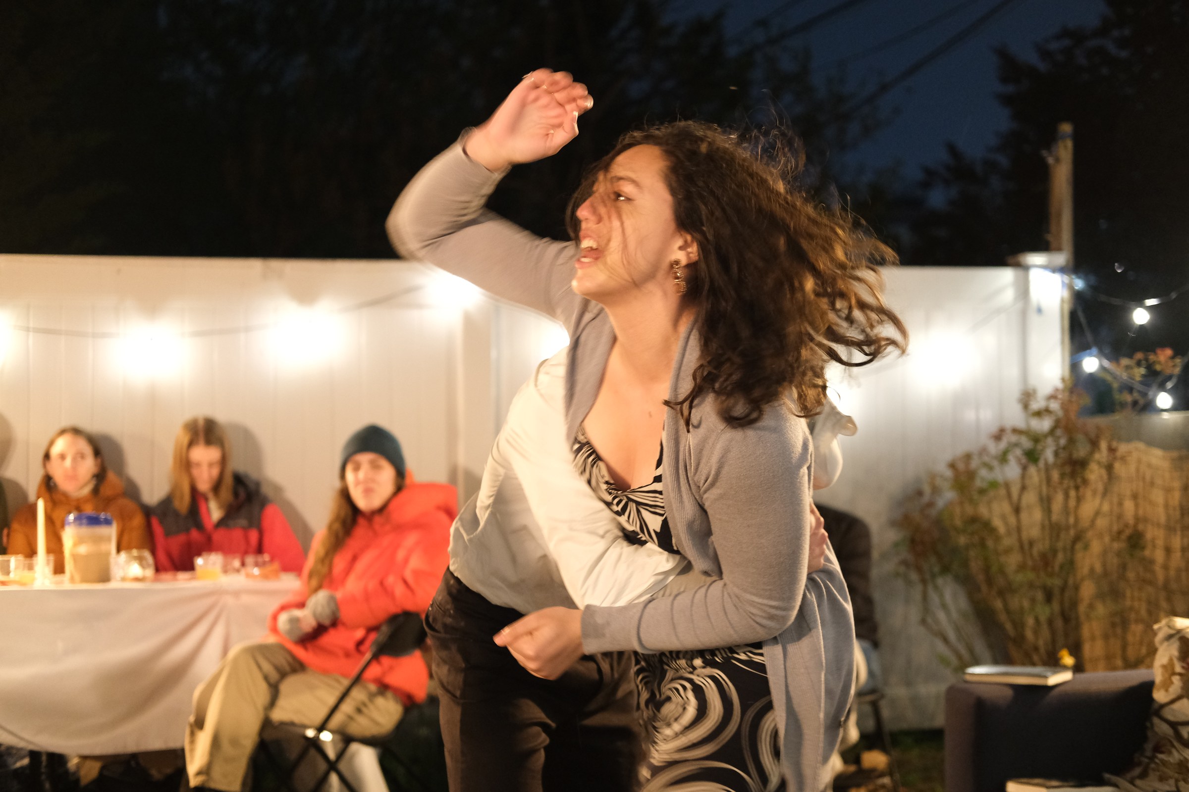 Martha moves through the backyard playing space with audience members behind her