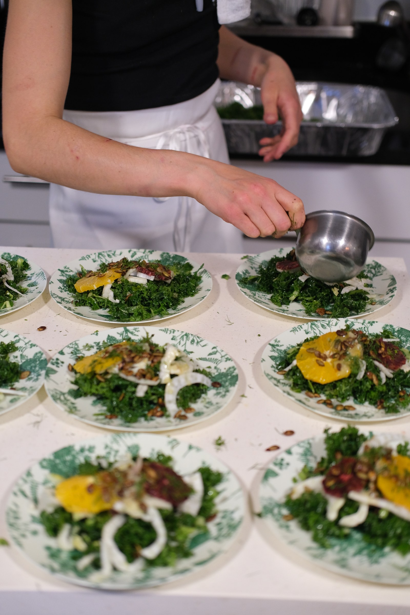 Kale and fennel salads being plated for the first course