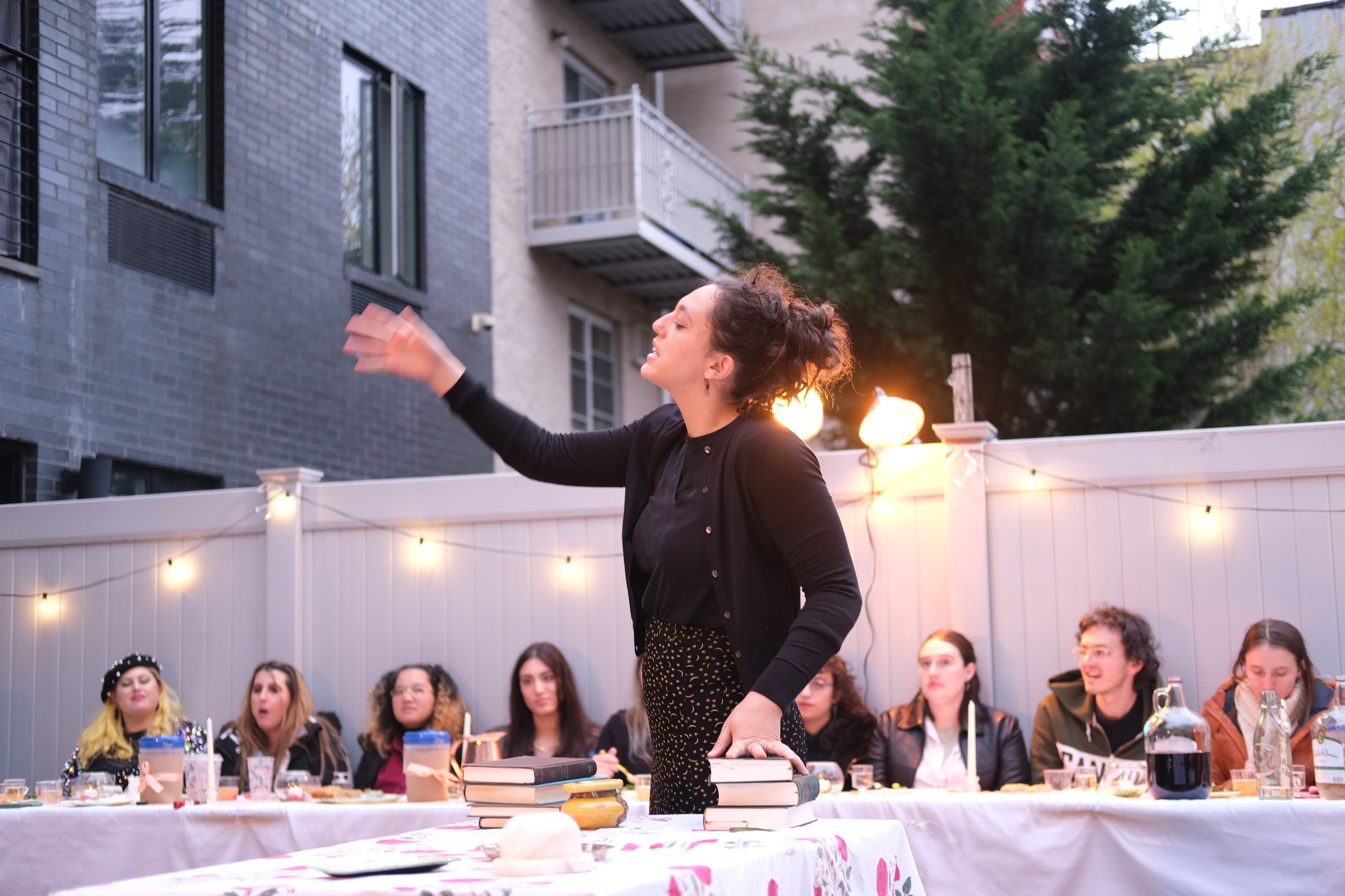 A performer addresses guests seated at a long dinner table